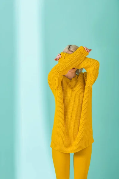 Vista oscurata della donna in maglione giallo e collant in posa su sfondo blu — Foto stock