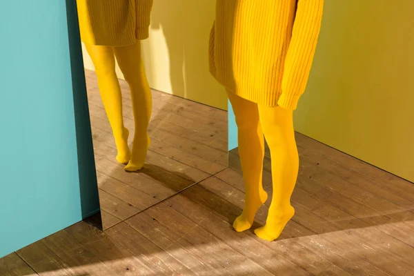 Schnappschuss einer Frau in gelbem Pullover und Strumpfhose, die am Spiegel steht — Stockfoto