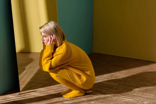 Молода стильна жінка в жовтому светрі і колготках сидить у дзеркалі — стокове фото