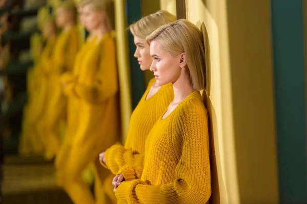 Selective focus of blond woman in yellow sweater and tights standing at mirror with her reflection in it — Stock Photo