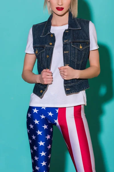 Обрізаний знімок стильною жінкою у білій сорочці, джинсові куртки і гетри з американським прапором patternon синій тлі — стокове фото