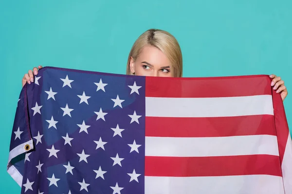 Vista oscurecida de la mujer con bandera americana mirando hacia otro lado sobre el telón de fondo azul, celebrando el concepto del 4 de julio - foto de stock