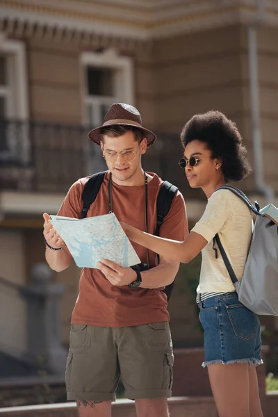 Multicultural couple of tourists with map looking for destination — Stock Photo