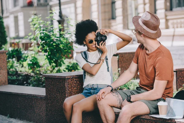 Jeune voyageuse prenant en photo son petit ami à la caméra — Photo de stock