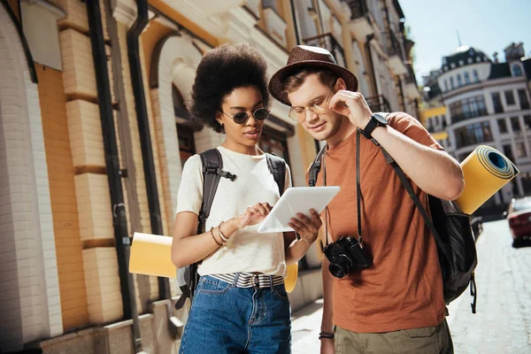 African american female traveler in sunglasses holding digital tablet and her boyfriend looking for destination — Stock Photo