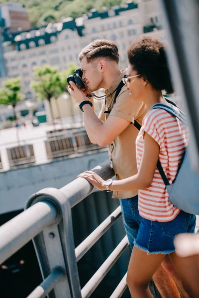 Viaggiatore maschio scattare foto sulla macchina fotografica e la sua ragazza in piedi vicino — Foto stock