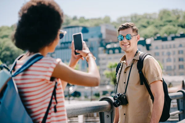 Женщина-путешественница фотографирует парня на смартфоне — стоковое фото