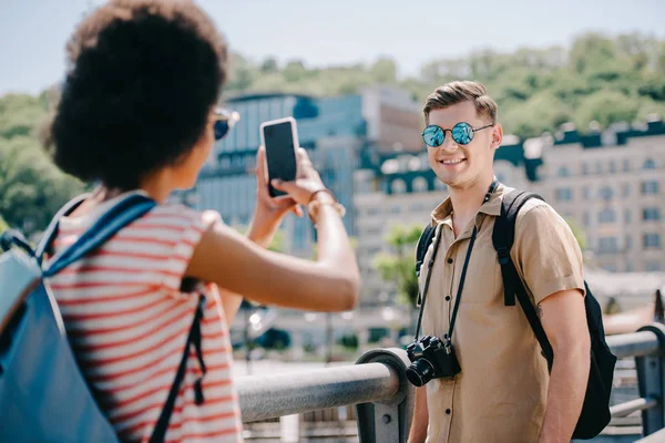 Voyageuse prenant en photo son petit ami sur smartphone — Photo de stock