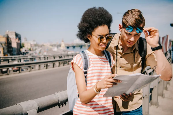 Multiethnic young couple of tourists looking at map — Stock Photo