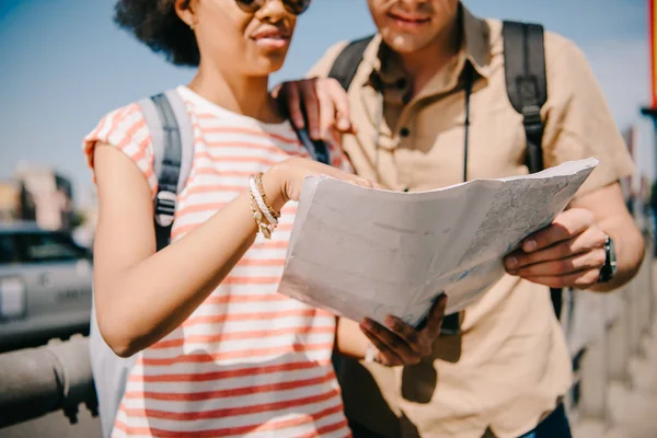 Cropped shot of couple of tourists looking and pointing at map — Stock Photo