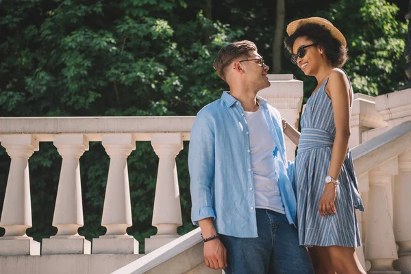 Young african american woman and stylish boyfriend standing on stairs in park — Stock Photo