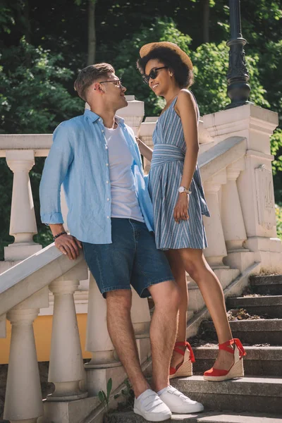 Feliz jovem casal de pé em escadas no parque — Fotografia de Stock