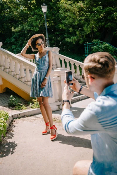 Mann fotografiert junge afrikanisch-amerikanische Freundin auf Smartphone — Stockfoto