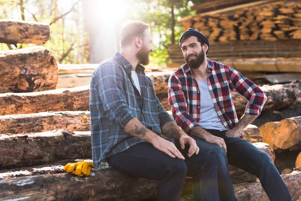 Zwei lächelnde bärtige Holzfäller im Gespräch miteinander im Sägewerk — Stockfoto