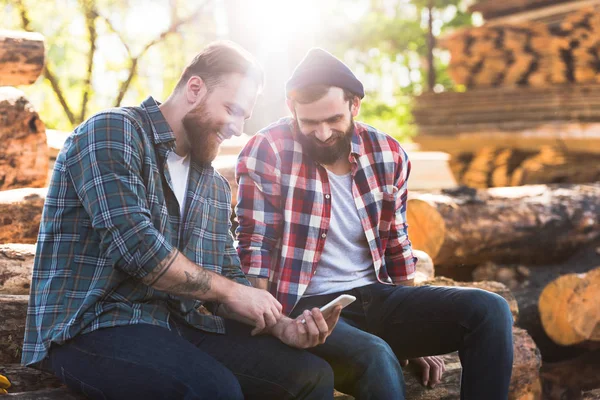 Smiling bearded lumberjacks looking at smartphone screen — Stock Photo