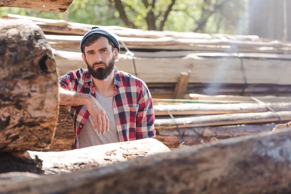 Bärtiger Holzfäller im karierten Hemd steht vor Sägewerk — Stockfoto