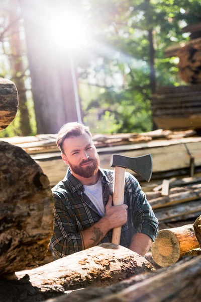 Holzfäller im karierten Hemd mit tätowierter Hand hält Axt an Sägewerk — Stockfoto