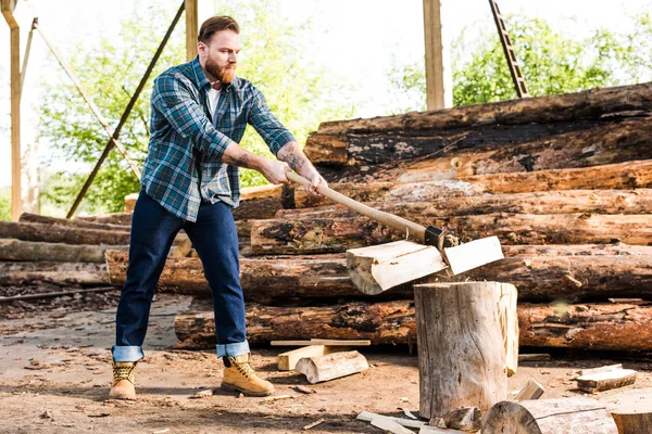 Lumberjack in checkered shirt chopping log at sawmill — Stock Photo