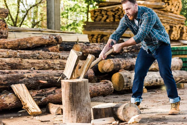 Lumberjack in checkered shirt chopping log at sawmill — Stock Photo