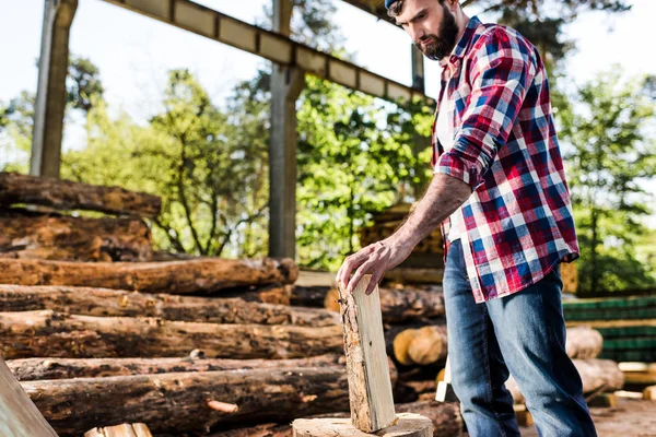 Holzfäller im karierten Hemd bereitet sich darauf vor, im Sägewerk die Hälfte des Stammes zu hacken — Stockfoto