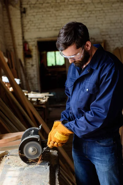 Handwerker in Schutzbrille und Handschuhen mit Schleifmaschine im Sägewerk — Stockfoto