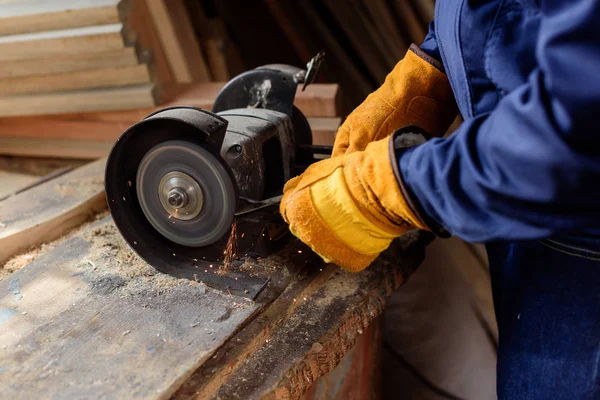 Cropped shot of craftsman in protective gloves using grinding machine at sawmill — Stock Photo