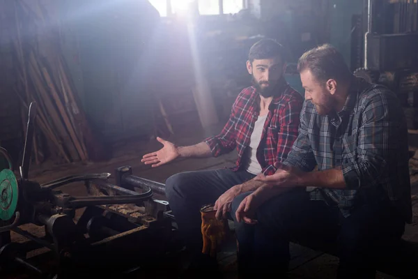 Bearded worker pointing on machine to colleague at sawmill — Stock Photo