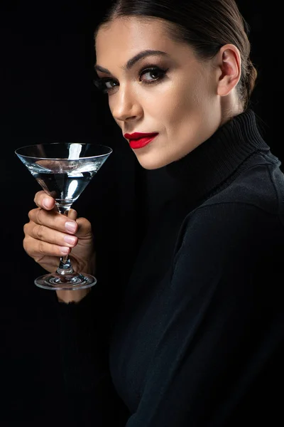 Bela mulher elegante com lábios vermelhos segurando vidro martini isolado em preto — Fotografia de Stock