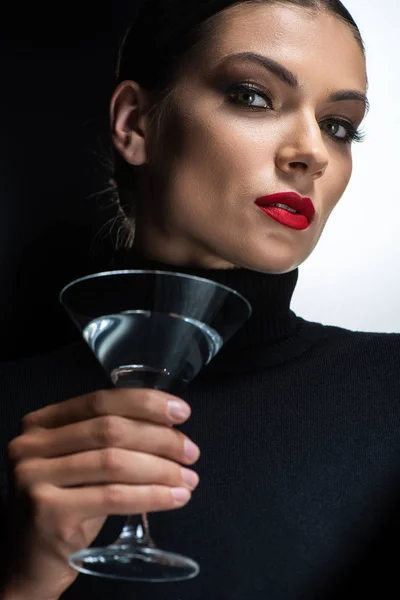 Hermosa mujer elegante con labios rojos sosteniendo martini y mirando a la cámara aislada en blanco y negro - foto de stock