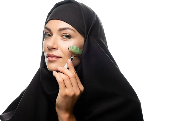 Jeune femme musulmane en hijab en utilisant un rouleau de jade isolé sur blanc — Photo de stock