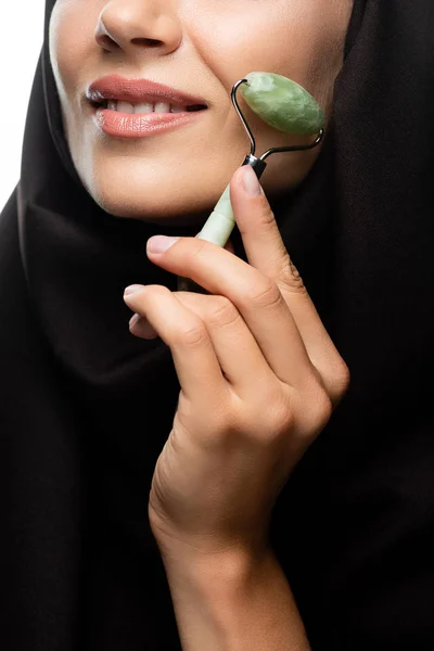 Vista ritagliata di giovane donna musulmana in hijab utilizzando rullo di giada isolato su bianco — Foto stock