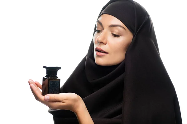 Young Muslim woman in hijab holding bottle of perfume isolated on white — Stock Photo