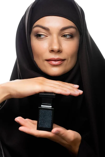 Young Muslim woman in hijab holding bottle of perfume isolated on white — Stock Photo