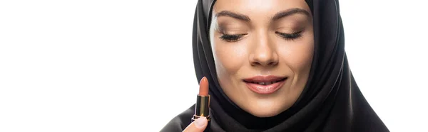 Young Muslim woman in hijab holding beige lipstick isolated on white, panoramic shot — Stock Photo