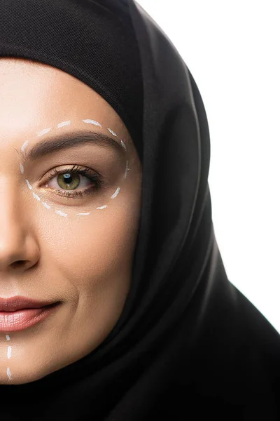 Vue recadrée de la jeune femme musulmane dans le hijab ayant des marques sur le visage pour la chirurgie plastique isolé sur blanc — Photo de stock