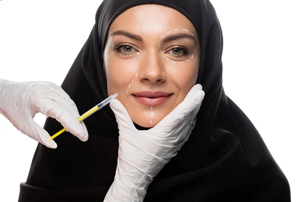 Sorridente jovem muçulmana no hijab com marcas no rosto tendo injeção de beleza isolada no branco — Fotografia de Stock