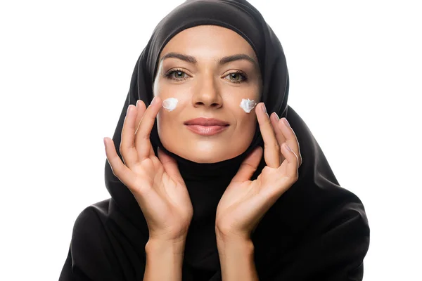 Jeune femme musulmane en hijab appliquer la crème cosmétique sur les poussins isolés sur blanc — Photo de stock
