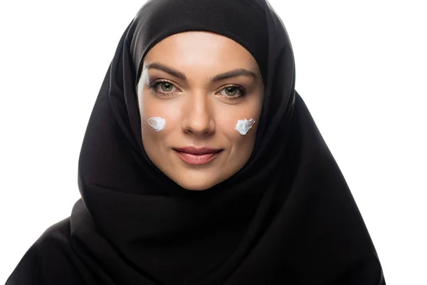 Jeune femme musulmane en hijab avec crème cosmétique sur les poussins isolés sur blanc — Photo de stock