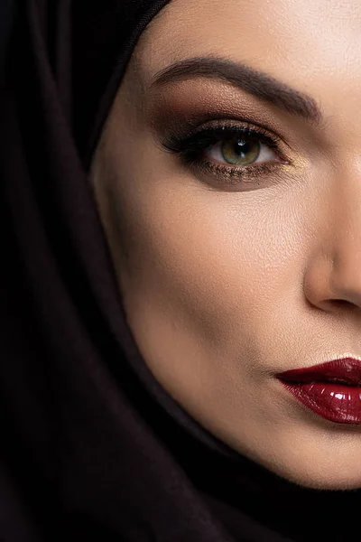 Vue rapprochée de la jeune femme musulmane en hijab avec des yeux fumés et des lèvres rouges isolées sur noir — Photo de stock