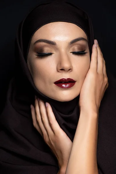 Jeune femme musulmane dans le hijab avec les yeux fermés, les yeux fumés et les lèvres rouges isolés sur noir — Photo de stock