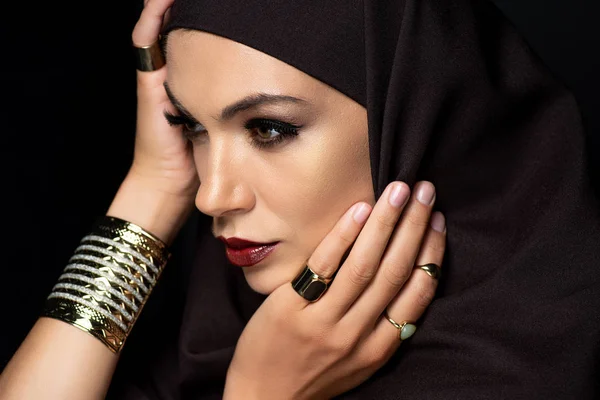 Вродлива мусульманка в Хіджабі з косметикою в золотих перснях і браслетах, ізольованих на чорному — стокове фото