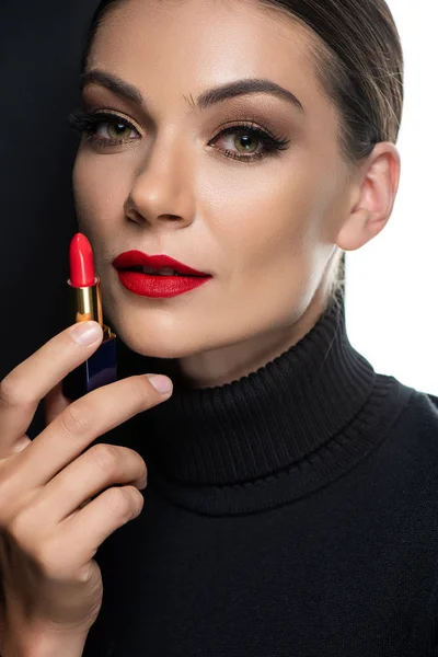 Hermosa mujer con labios rojos sosteniendo lápiz labial aislado en blanco y negro - foto de stock