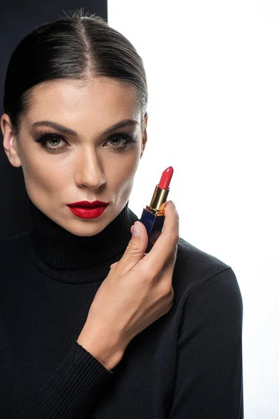 Hermosa mujer con labios rojos sosteniendo lápiz labial aislado en blanco y negro - foto de stock