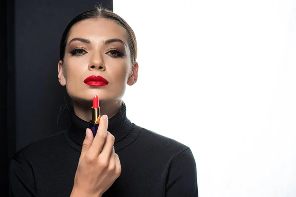 Belle femme avec des lèvres rouges tenant rouge à lèvres isolé sur blanc et noir — Photo de stock