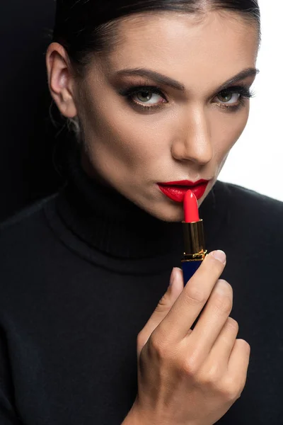 Hermosa mujer con labios rojos aplicando lápiz labial aislado en blanco y negro - foto de stock