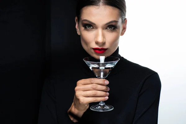 Красивая женщина с красными губами держа мартини изолированы на белом и черном — стоковое фото