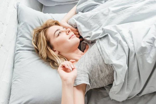 Blick von oben auf die schöne junge Frau, die zu Hause auf dem Bett liegt — Stock Photo