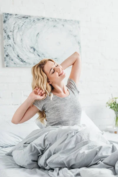 Весела жінка посміхається під час пробудження в спальні — стокове фото