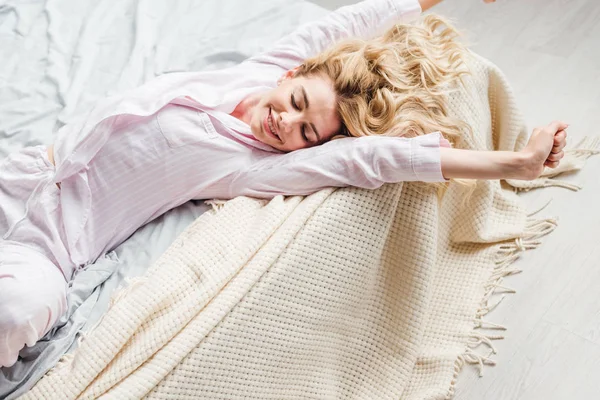 Fröhliche Frau mit geschlossenen Augen auf dem Bett liegend — Stockfoto