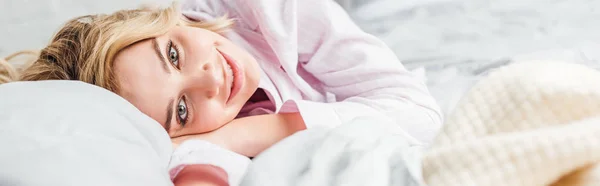 Panoramic shot of cheerful girl looking at camera in bedroom — Stock Photo